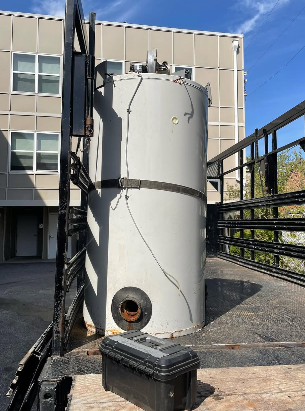 Old failed commercial water heater being hauled out on a flatbed